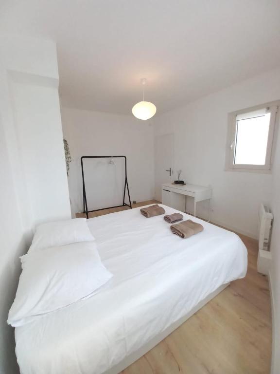Cette chambre blanche comprend un grand lit blanc et une fenêtre. dans l'établissement Le 29 , 4pers, 2 lits, climatisation et wif, à Agen