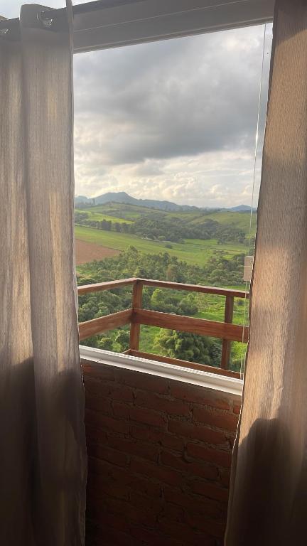 une fenêtre avec vue sur un champ et une clôture dans l'établissement Chacrinha pousada e restaurante Chalé Seriema, à Caldas Novas