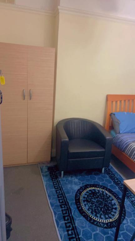 una camera con sedia, letto e armadio di Ruby Rooms a Slough