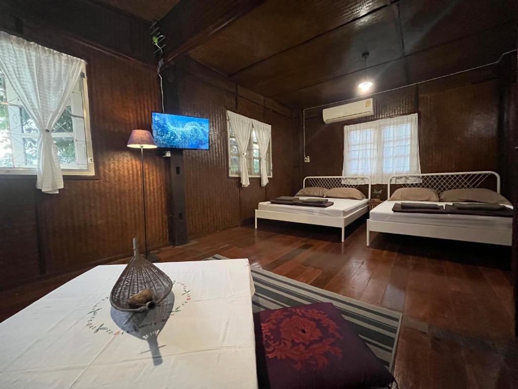 a living room with two beds and a tv at Once in Lampang Guesthouse in Lampang