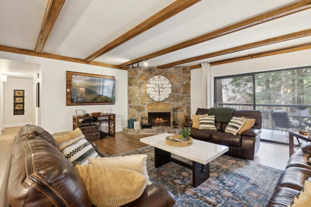 a living room with leather furniture and a stone fireplace at Superb Gatlinburg Condo with Pool Table and private balcony with stream views in Gatlinburg