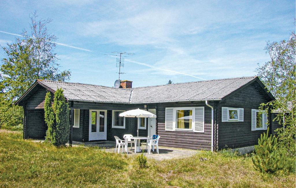 a small black house with a table and an umbrella at Kanalhytten in Rømø Kirkeby