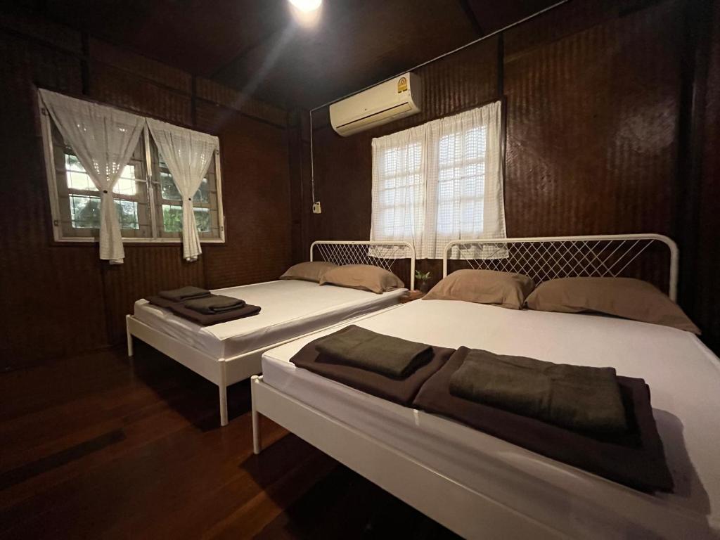 two beds in a room with two windows at Once in Lampang Guesthouse in Lampang