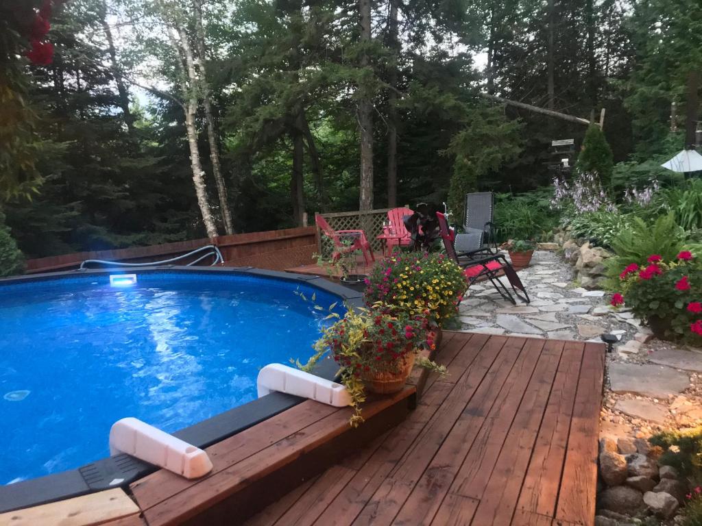 a swimming pool on a wooden deck with plants on it at PETIT COIN DE PARADIS in Sainte Anne des Lacs