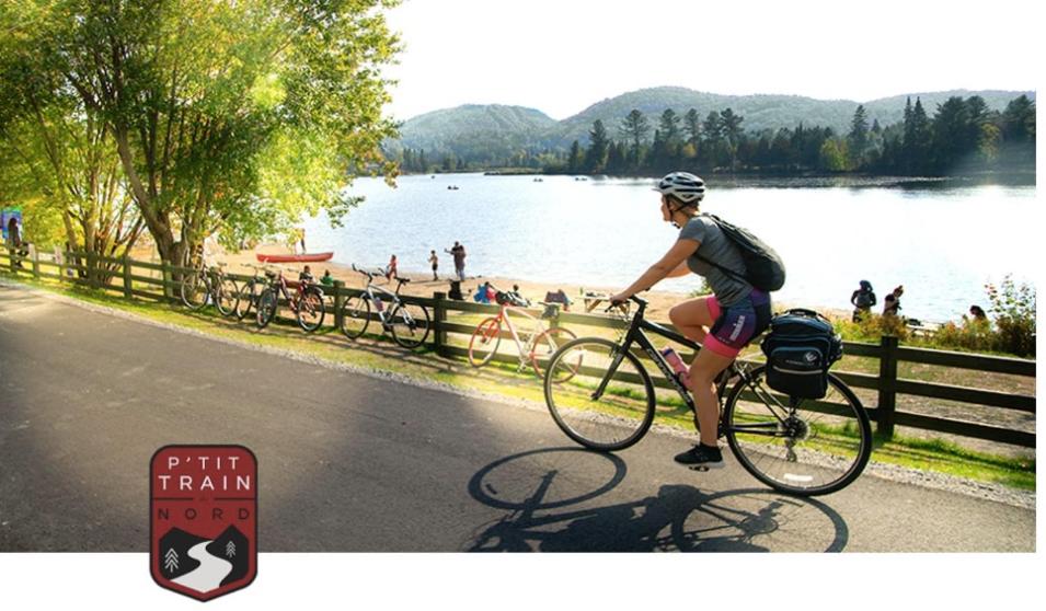 a person riding a bike next to a body of water at PETIT COIN DE PARADIS in Sainte Anne des Lacs