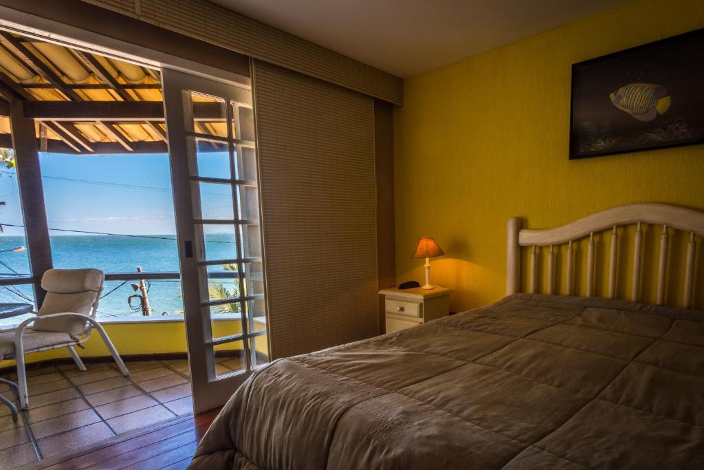 a bedroom with a bed and a view of the ocean at Pousada Pontal da Praia in São Pedro da Aldeia