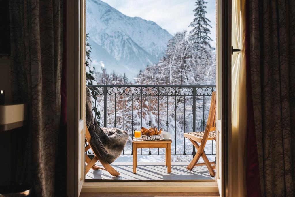 a room with a balcony with a view of a snowy mountain at Hôtel Mont-Blanc Chamonix in Chamonix