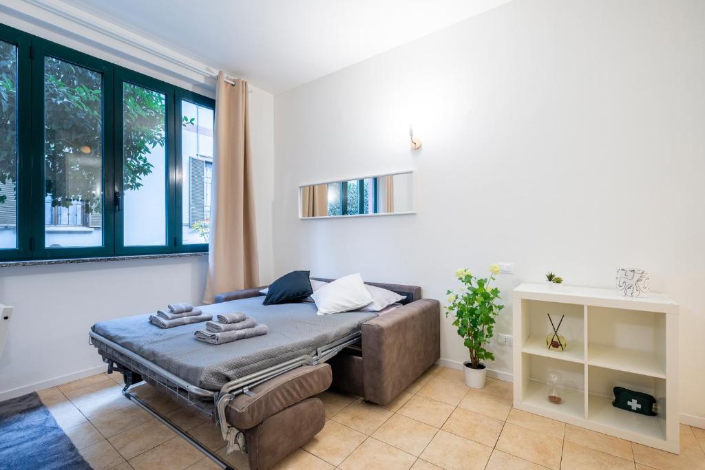 una camera con letto, divano e finestre di Giardino a Milano - Elegante Appartamento a Milano