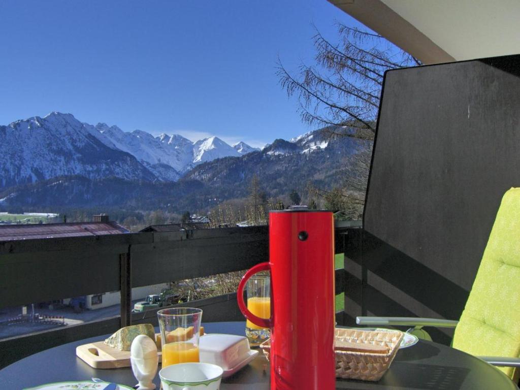 einen Tisch mit einer roten Thermoskanne auf einem Balkon mit Bergblick in der Unterkunft Almsternchen 1 in Oberstdorf