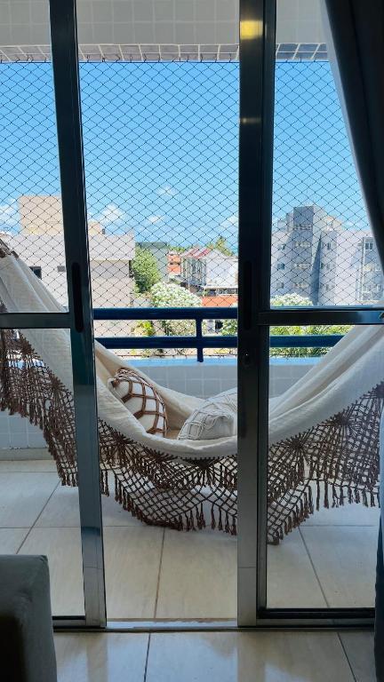 a hammock on a balcony with a view of the city at Apto Lindo e Amplo, 150m Praia in Cabedelo