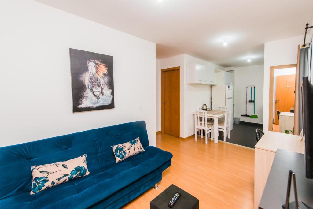a living room with a blue couch and a kitchen at Acomodações Azaleias by Rental in Palhoça