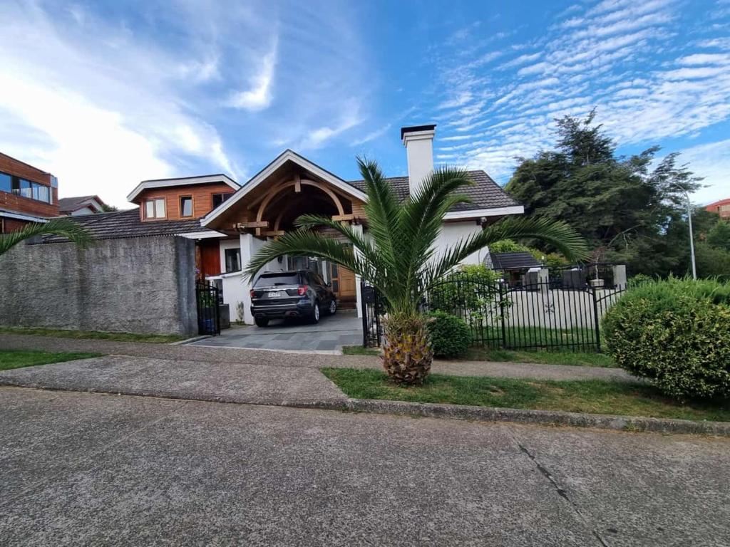 a house with a palm tree in a driveway at Habitaciones Dobles Valdivia, Isla Teja in Valdivia