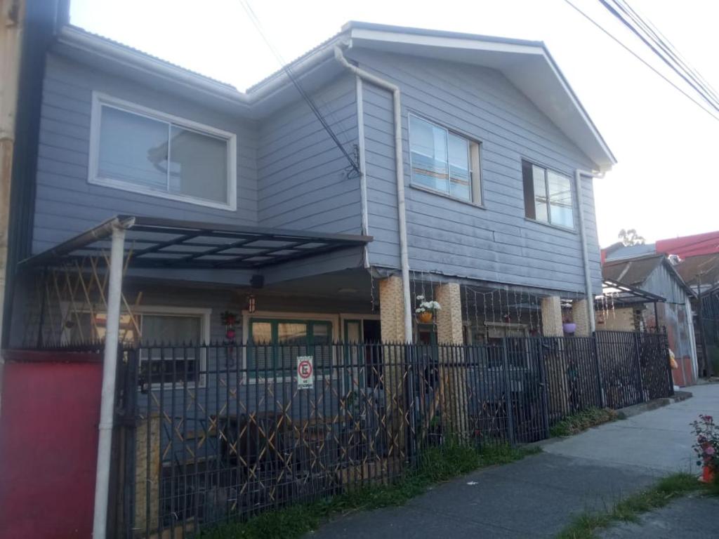 a house with a fence in front of it at Vintage Hostal in Puerto Montt
