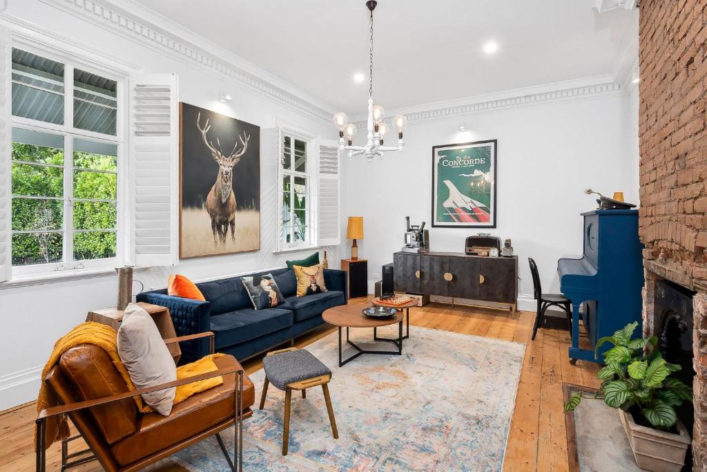 een woonkamer met een blauwe bank en een open haard bij Gable House Geelong in Geelong