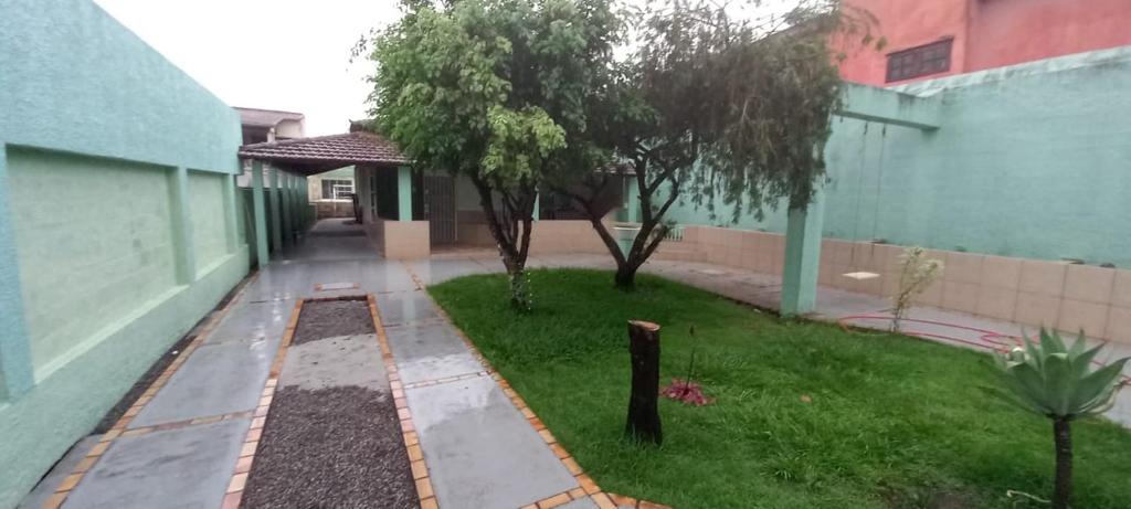 a garden with two trees next to a building at Casa no Centro in Rio das Ostras