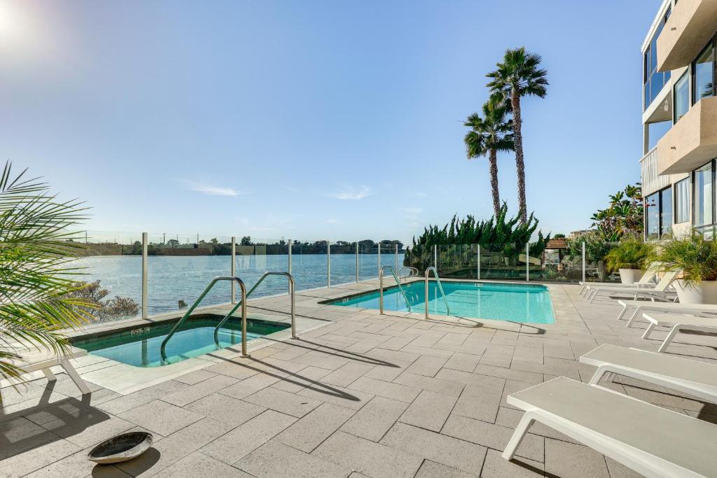 a swimming pool with tables and chairs next to the water at Waterfront Condo with Dock Access in Carlsbad! in Carlsbad