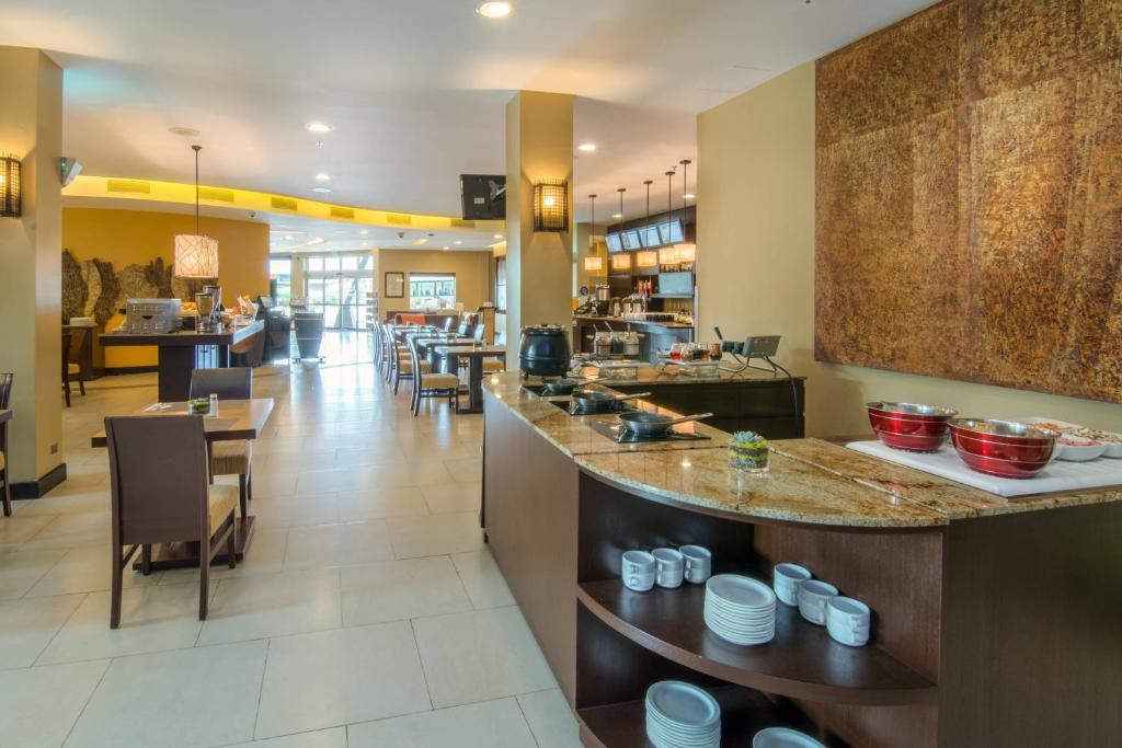 a restaurant with a counter with dishes on it at Courtyard by Marriott San Jose Airport Alajuela in Alajuela City