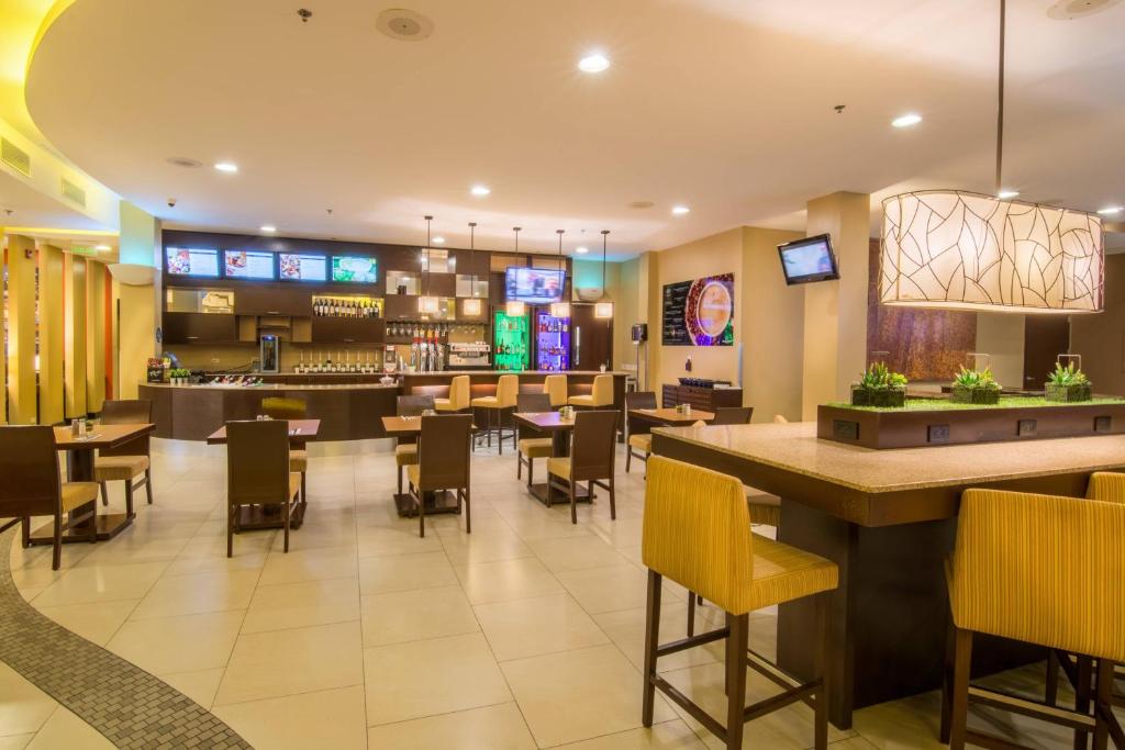 a restaurant with a bar and tables and chairs at Courtyard by Marriott San Jose Airport Alajuela in Alajuela City