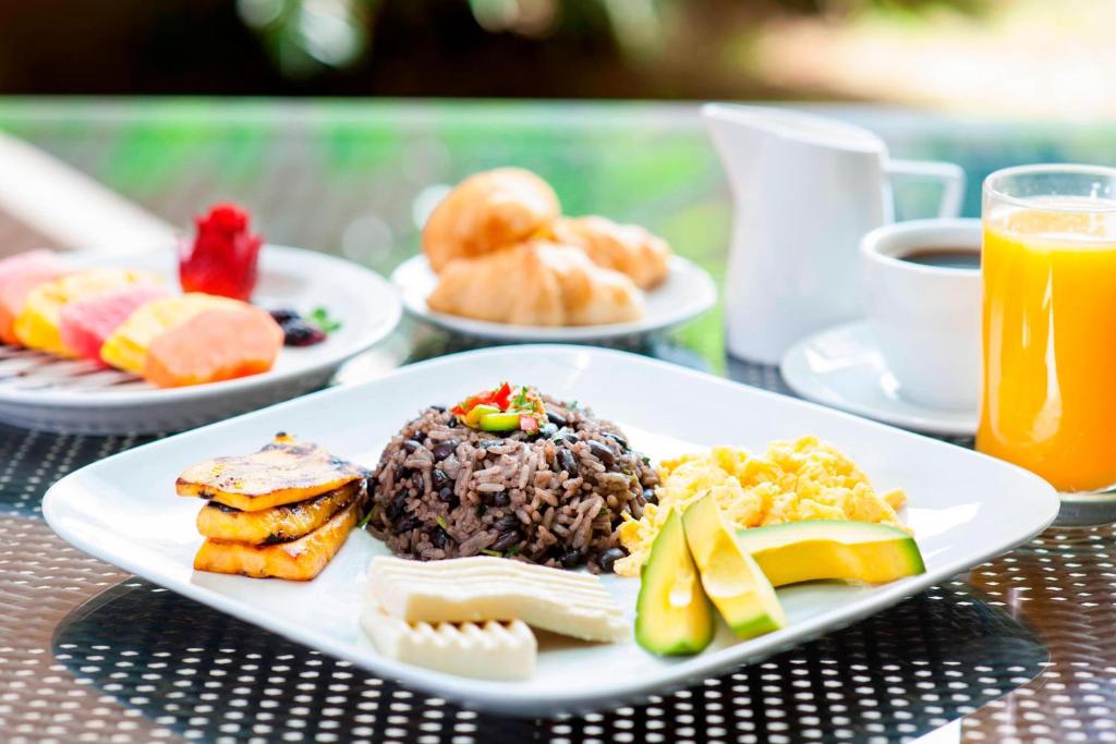 a plate of breakfast food on a table with orange juice at Courtyard by Marriott San Jose Airport Alajuela in Alajuela City