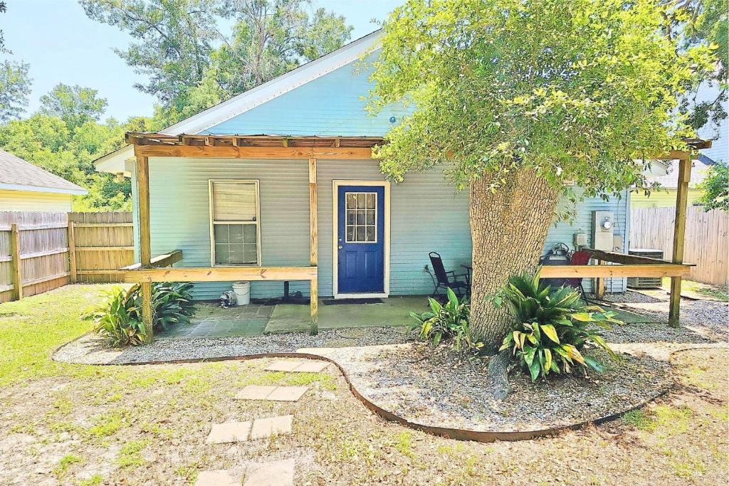 a small house with a blue door and a tree at 24th Street House in Gulfport