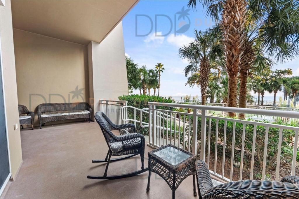 balcone con sedie, tavolo e palme di Legacy Tower Two 107 Deluxe a Gulfport