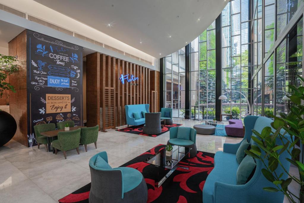 A colorful lobby lounge with blue seating, café-style signage and tall glazed windows.