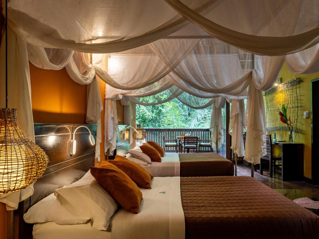 1 dormitorio con 2 camas, cortinas y ventana en Tambopata Research Center, en Tambopata