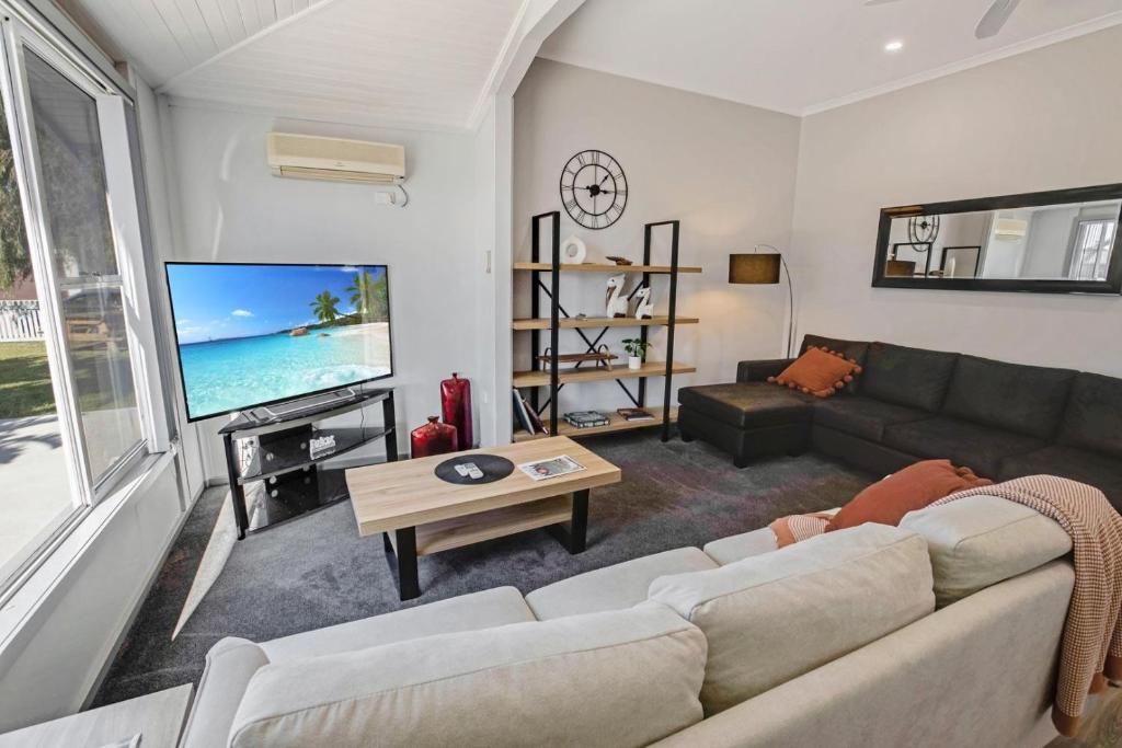 ein Wohnzimmer mit Couch und Flachbildfernseher in der Unterkunft Beach and Lakes Cottage A in Lakes Entrance