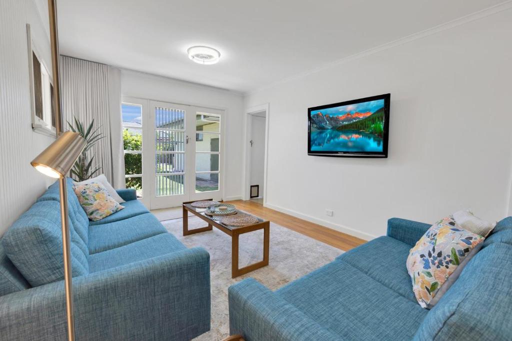a living room with two blue couches and a tv at Cearc House in Bairnsdale