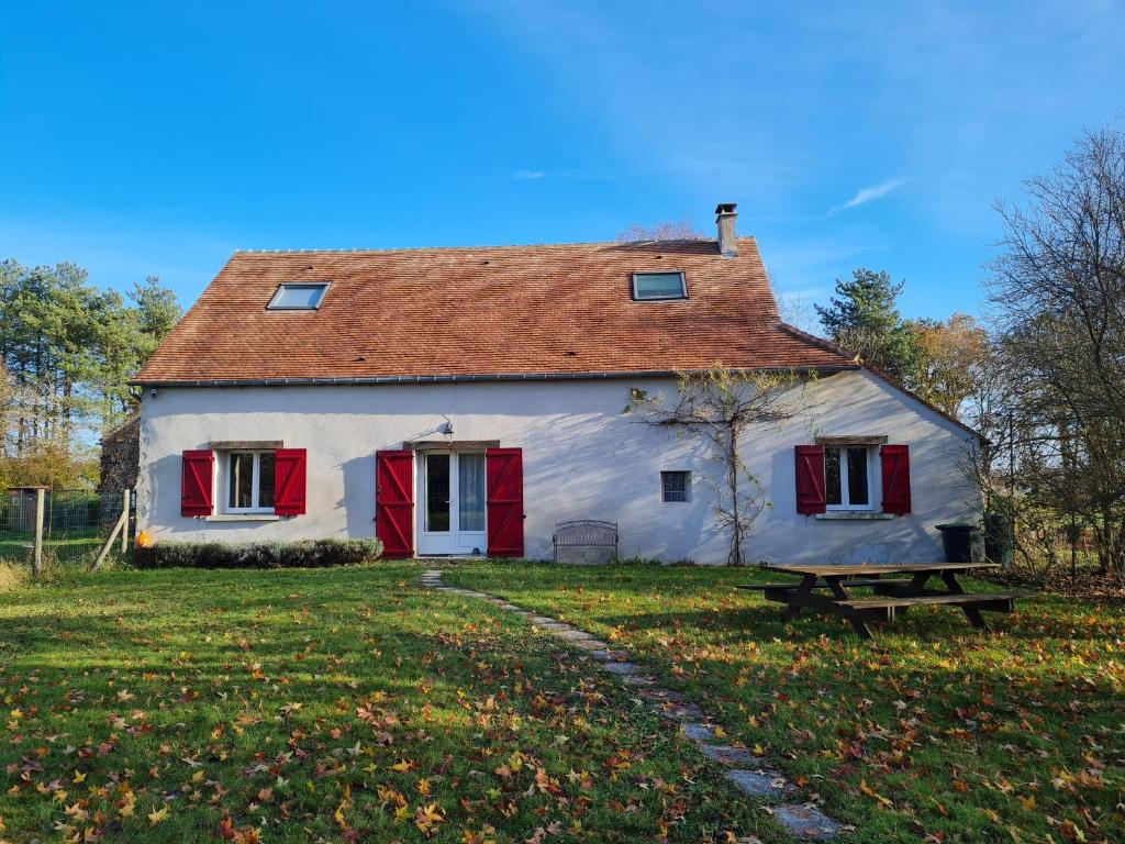 une grande maison blanche avec des volets rouges et un banc dans l'établissement Gîte de charme au Val de Loire, près d'Orléans - FR-1-590-534, à Donnery