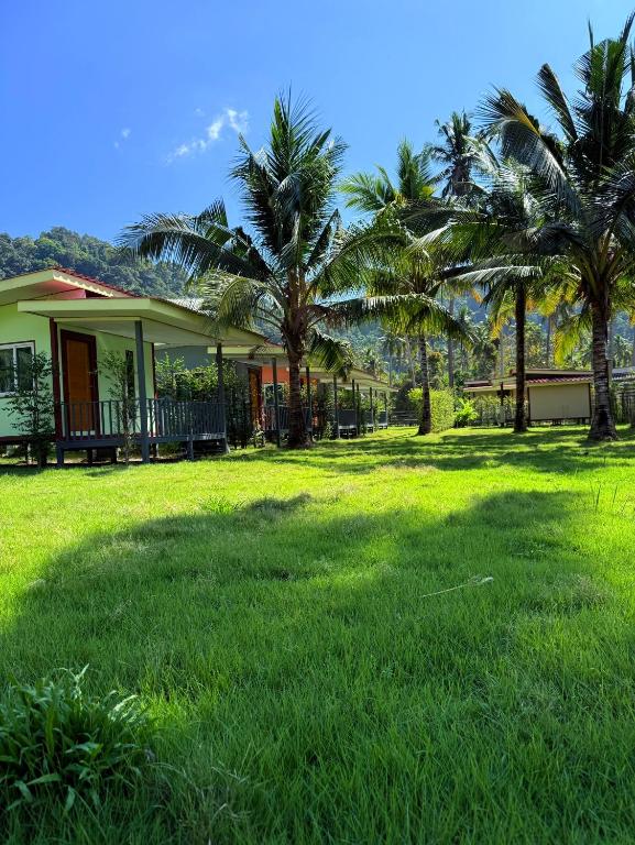 a house with palm trees in a field of grass at NgopaKohKoodResort in Ban Bang Bao