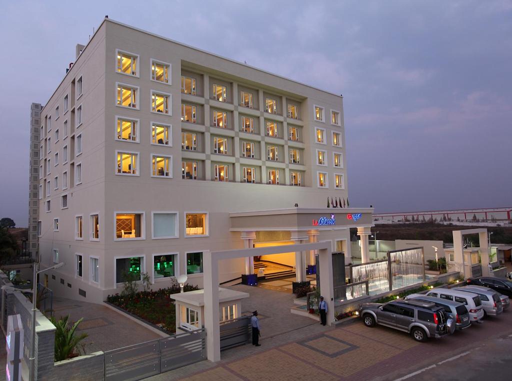 un gran hotel blanco con coches estacionados frente a él en La Classic- Attibele, Hosur, en Attibele