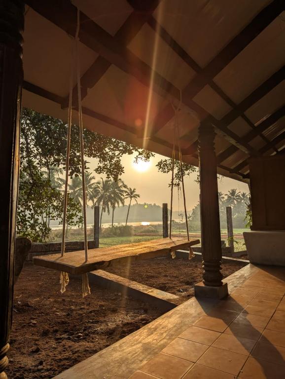 a porch swing with the sunset in the background at Svarna in Udupi