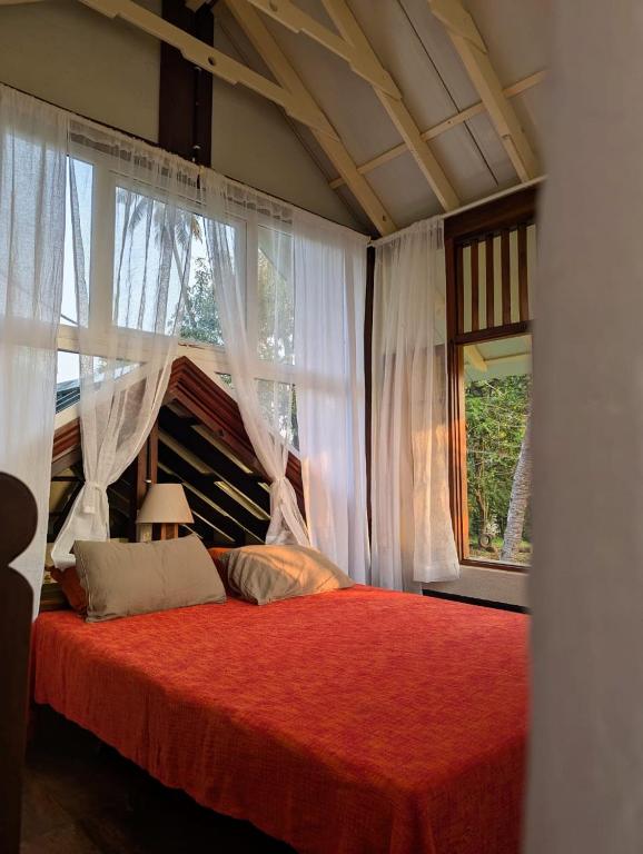a bedroom with a red bed with a window at Svarna in Udupi