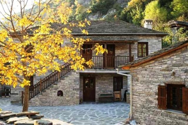 Casa de piedra con balcón y árbol en Terpsichori Guesthouse, en Kapesovo