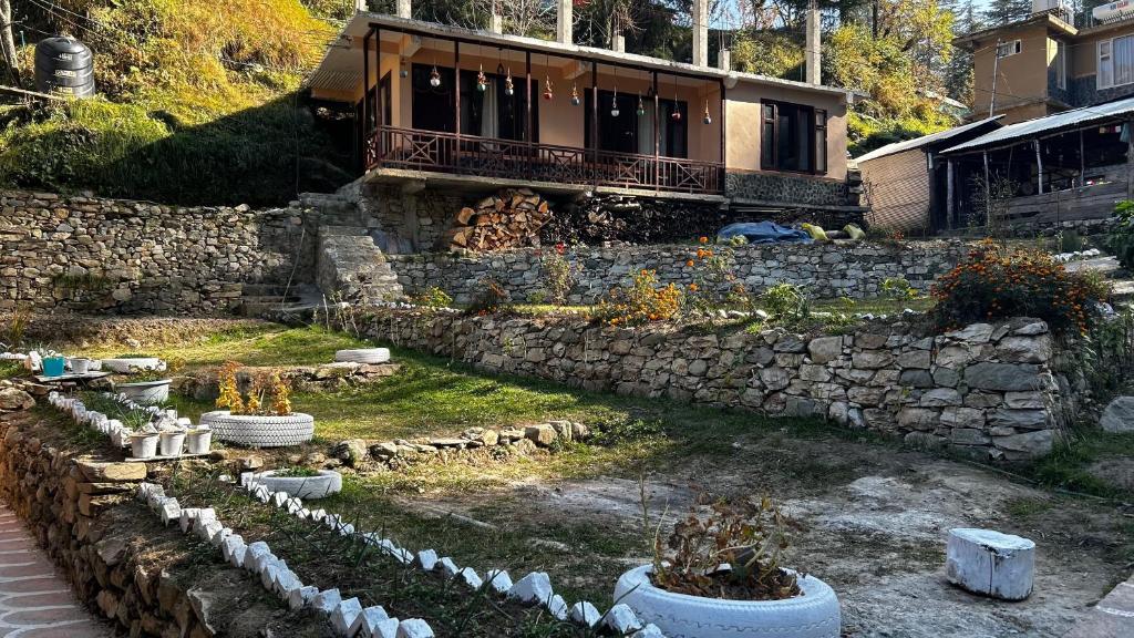 a garden in front of a house with a stone wall at PineNest Cottages & Cafe in Jibhi