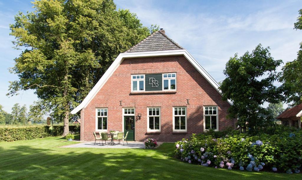 een groot rood bakstenen huis met een klok erop bij B&B De Beiert in Delden