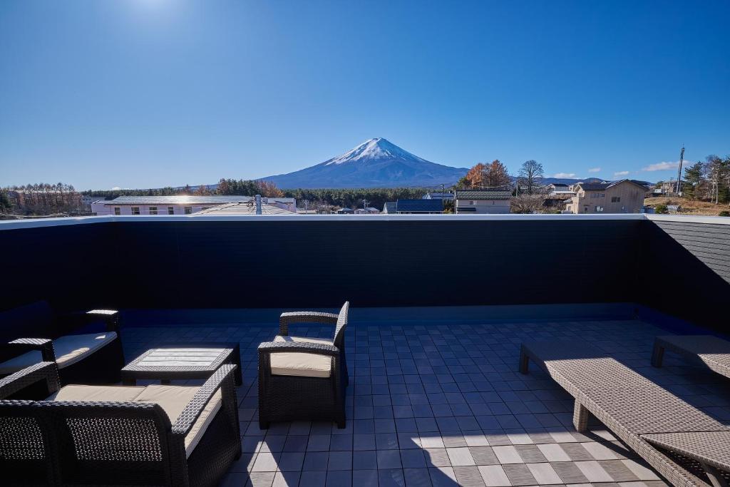 a patio with tables and chairs and a mountain in the background at MIYA HOUSE Funatsu B in Fujikawaguchiko