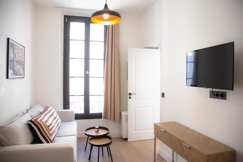 un salon avec un canapé et une télévision sur un mur dans l'établissement 2P au coeur du Vieil Antibes, à Antibes