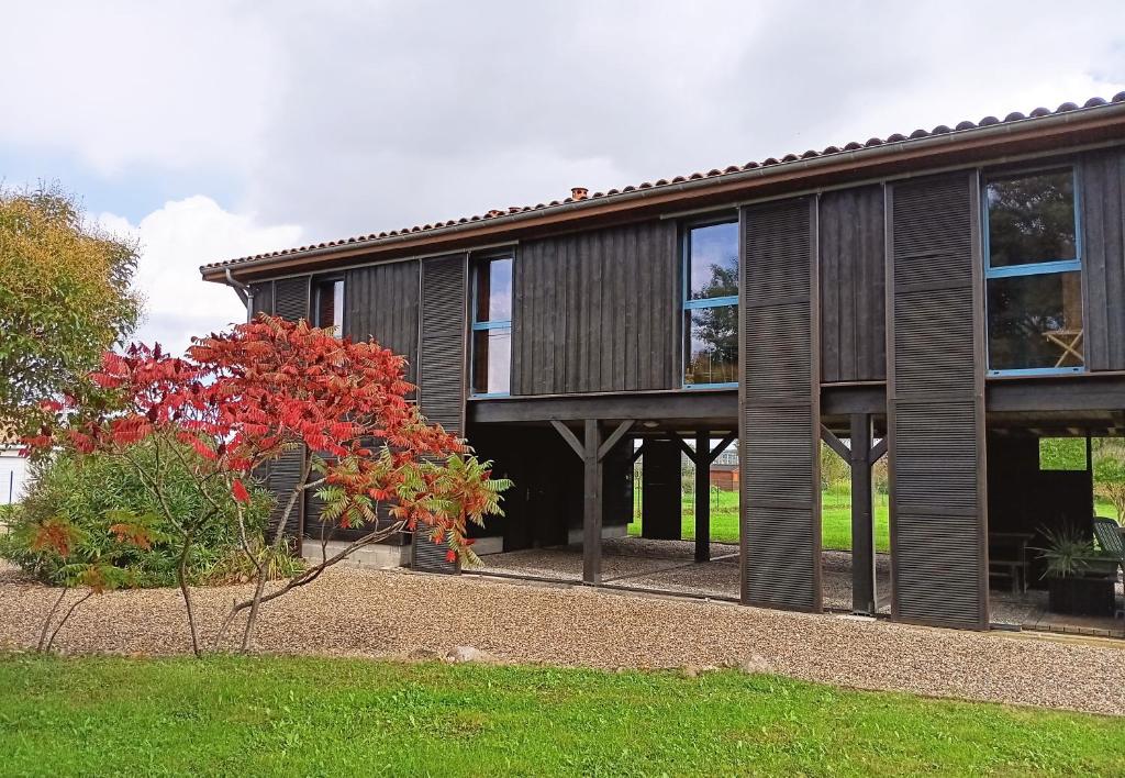 a wooden house with a tree in front of it at Le Séchoir Aquitain, logement insolite in Dolmayrac