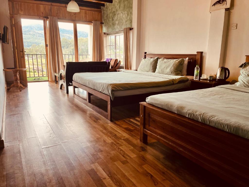 una camera d'albergo con due letti e una grande finestra di Medalin Lake Gregory a Nuwara Eliya