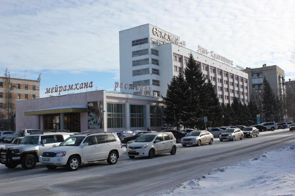 um parque de estacionamento com carros estacionados em frente a um edifício em Ust-Kamenogorsk Hotel em Ustʼ-Kamenogorsk