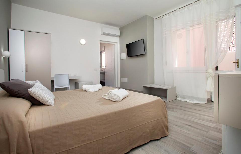 a bedroom with a large bed and a television at I Viaggi di Ki in Santa Teresa Gallura