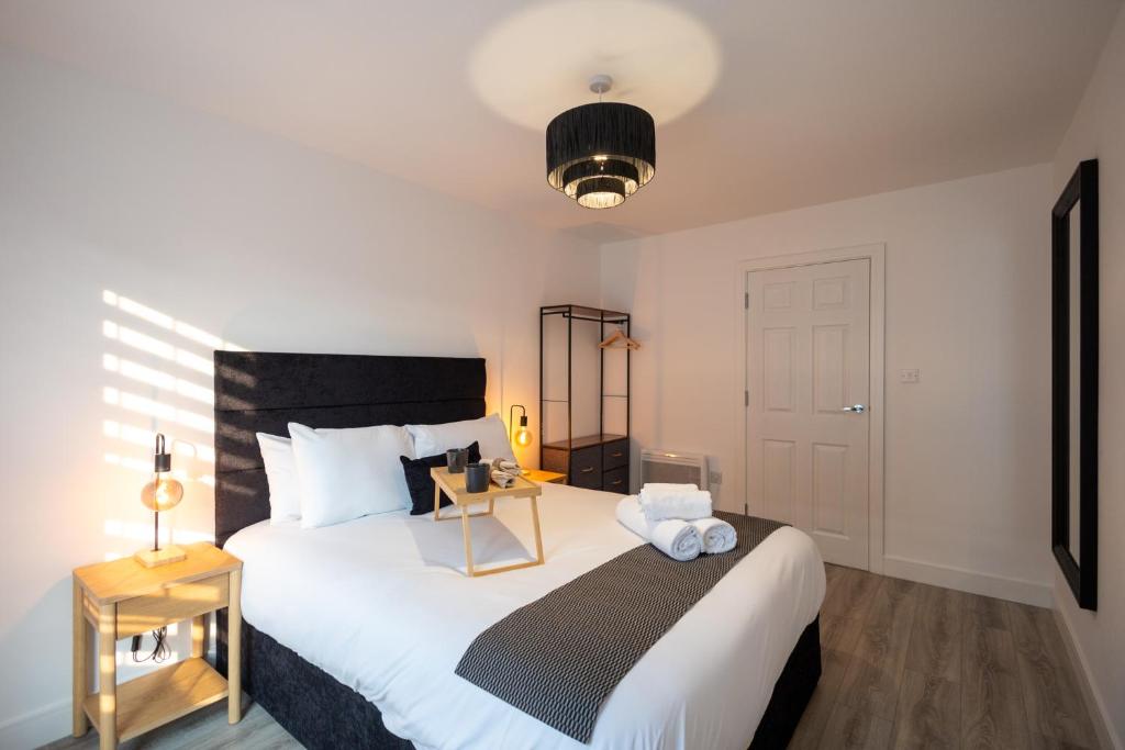 ein Schlafzimmer mit einem großen weißen Bett und einem Nachttisch in der Unterkunft Stylist 2-Bedroom Flat - Watford Central in Watford