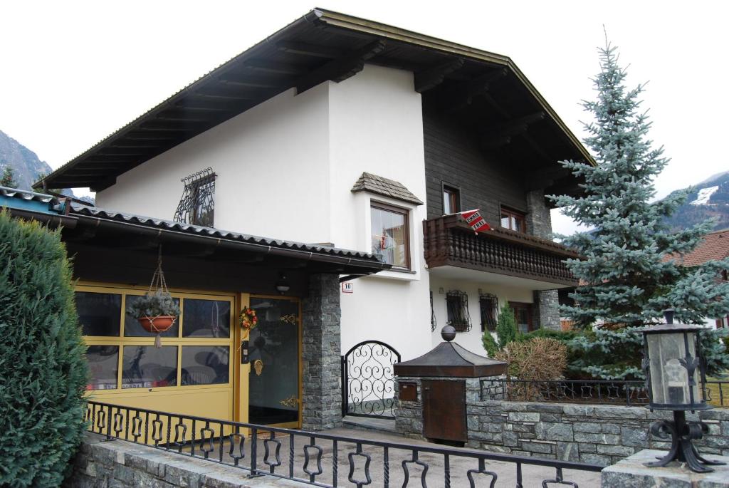 ein Haus mit gelber Tür und einem Zaun in der Unterkunft Ferienhaus Plattner in Lienz