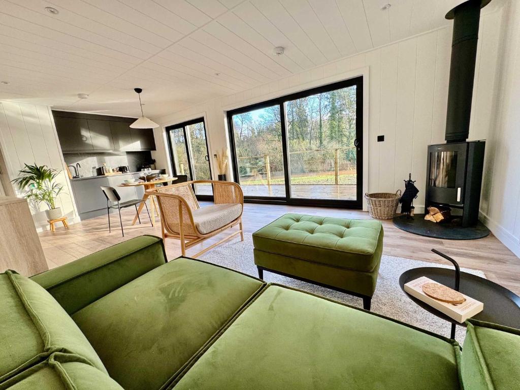 a living room with a green couch and a fireplace at Kingfisher - Luxurious Off-Grid Eco Cabin with Riverviews in Market Drayton