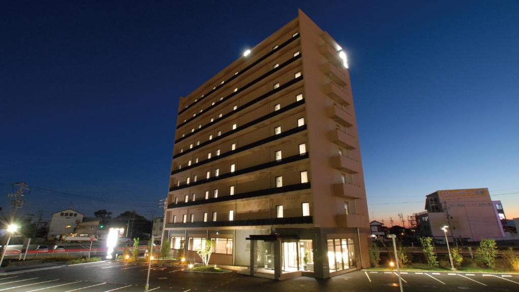 un edificio alto in un parcheggio di notte di AB Hotel Kakamigahara a Kakamigahara