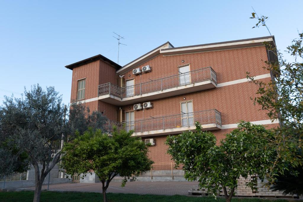 a red brick building with balconies and trees at Casa Bellavista in Siderno Marina