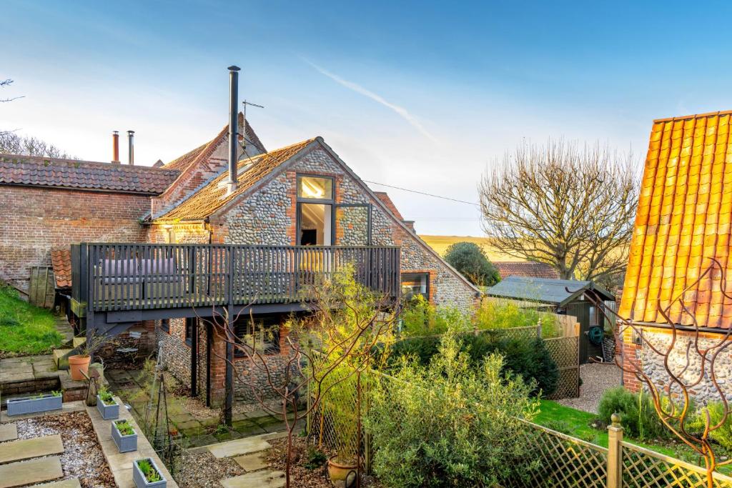 an old brick house with a balcony in a yard at Mill End by Big Skies Cottages in Weybourne