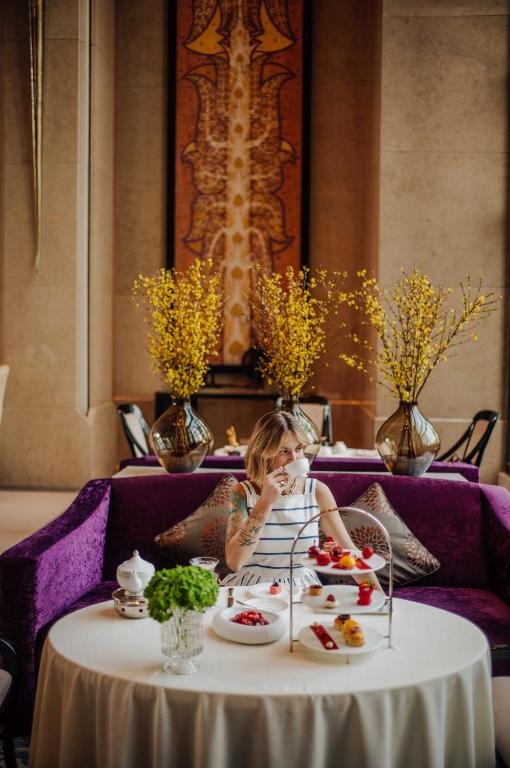 A child sits at a round table with a tiered afternoon-tea-style spread in an ornate lounge.